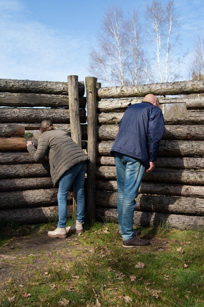 Twee mensen kijken door houten wallen