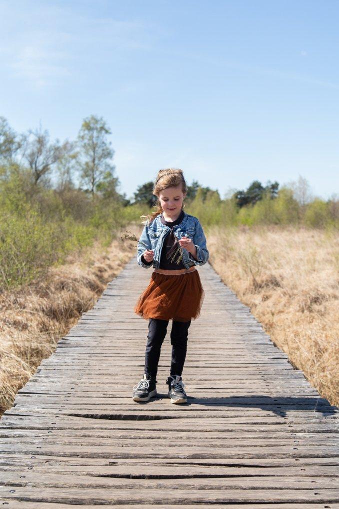 Meisje op knuppelbrug in landschap