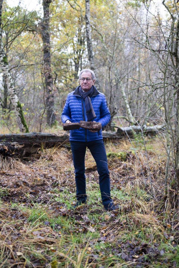 Man met turfplakken in handen in natuur