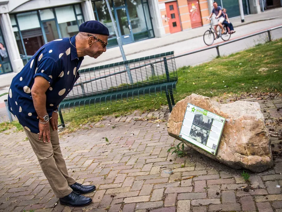 Man bij steen met informatiebord erop