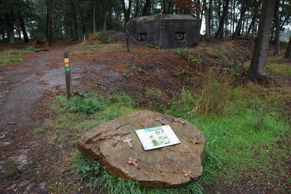 Landschap met kazemat en platte steen met bord en kruizen erop