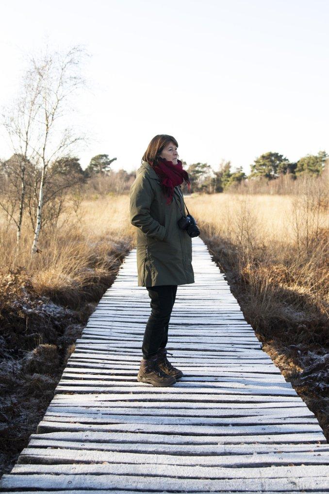 Vrouw met winterjas op knuppelbrug