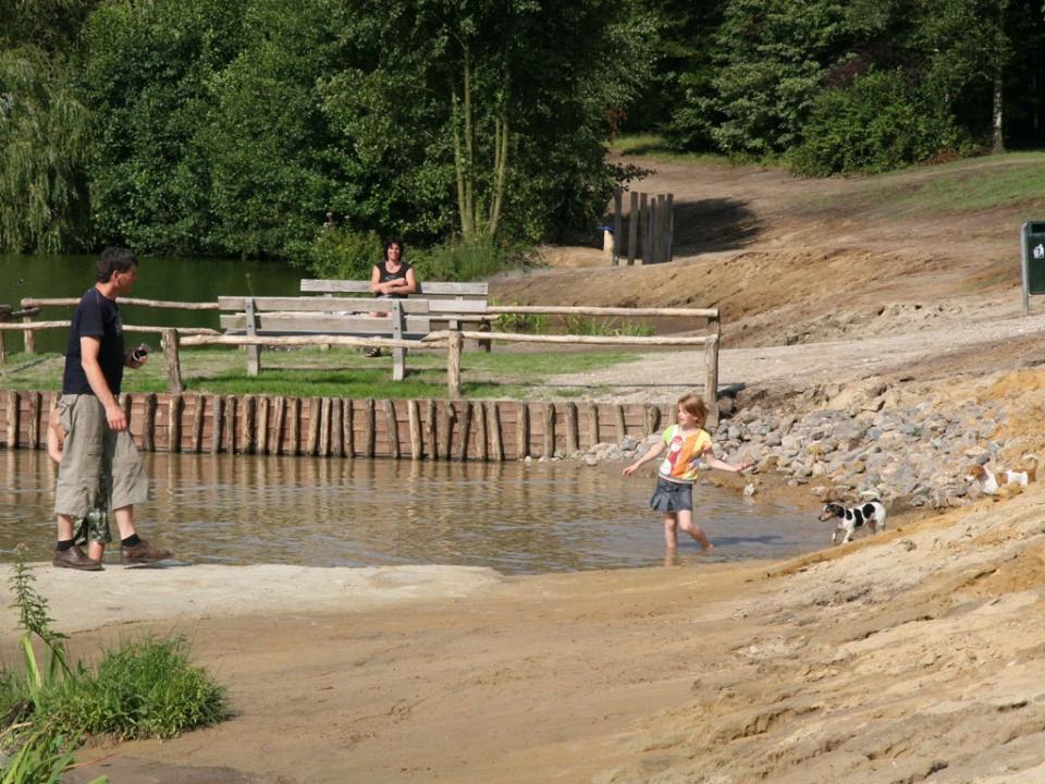 Man met kind bij waterplas met zandheuvel
