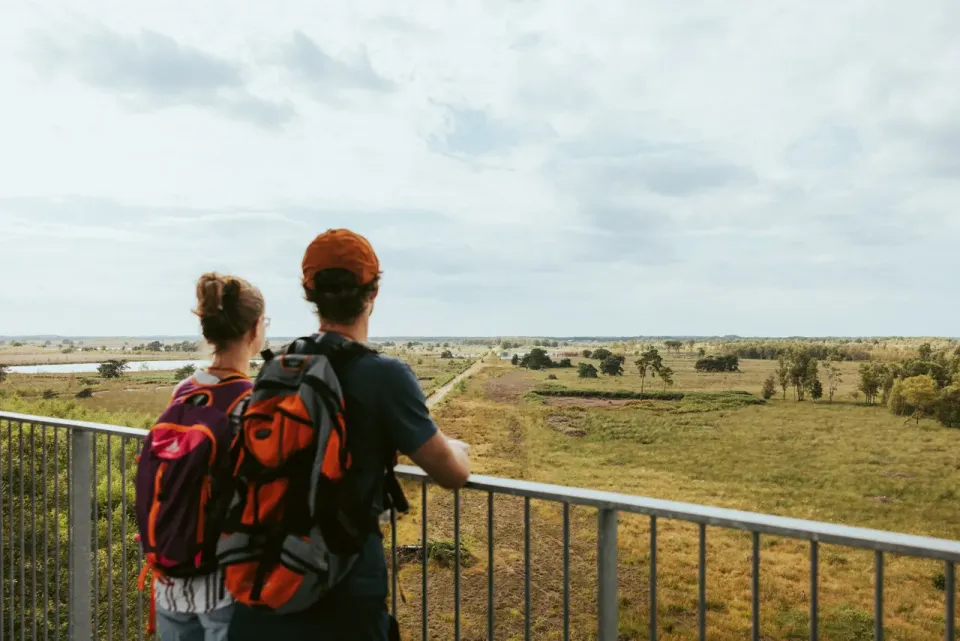 Man en vrouw kijken vanaf hoogte uit over landschap