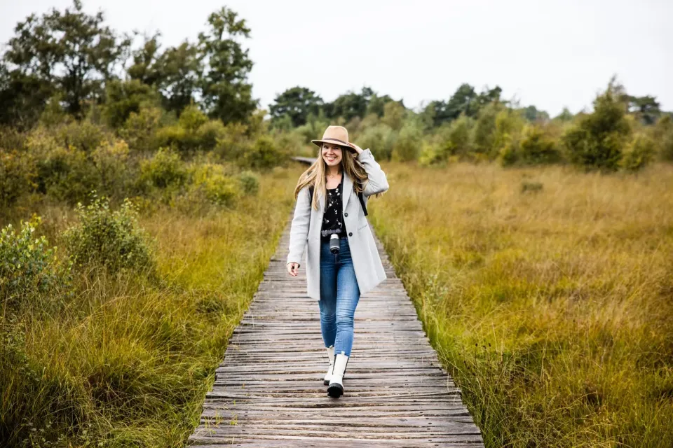 Vrouw met hoed loopt over knuppelbrug