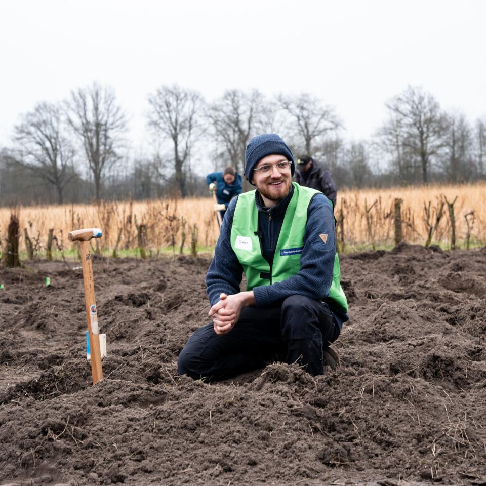 Jongere zit gehurkt naast schep in de grond